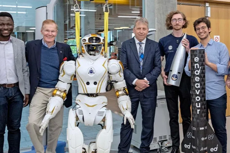 Seven people standing in a robotics lab, smiling with a humanoid robot.